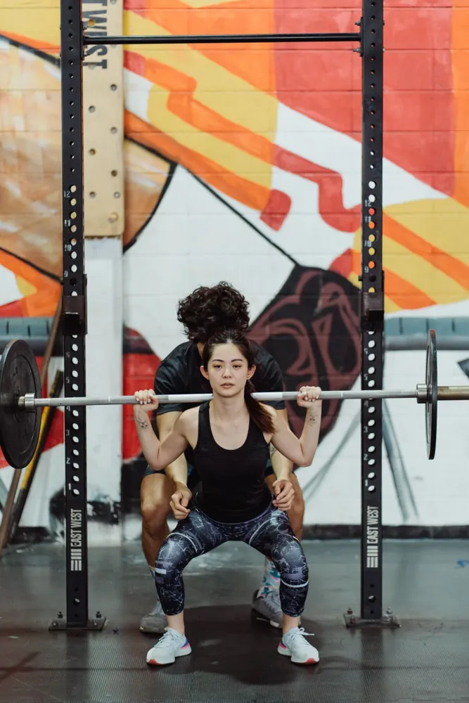 A woman training with a barbell and a coach